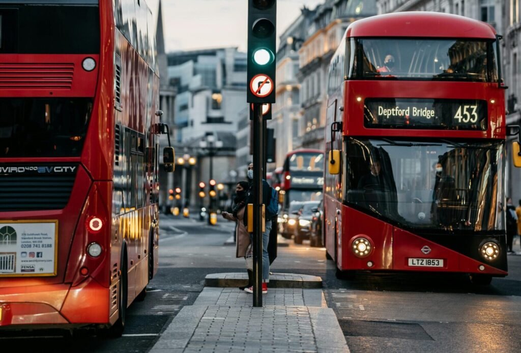London cityscape featuring iconic double-decker buses on a bustling street at dusk.