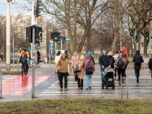 A lively city crosswalk with diverse pedestrians and cyclists on a winter day.