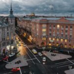 A vibrant city intersection with historic buildings at dusk, showcasing urban life.