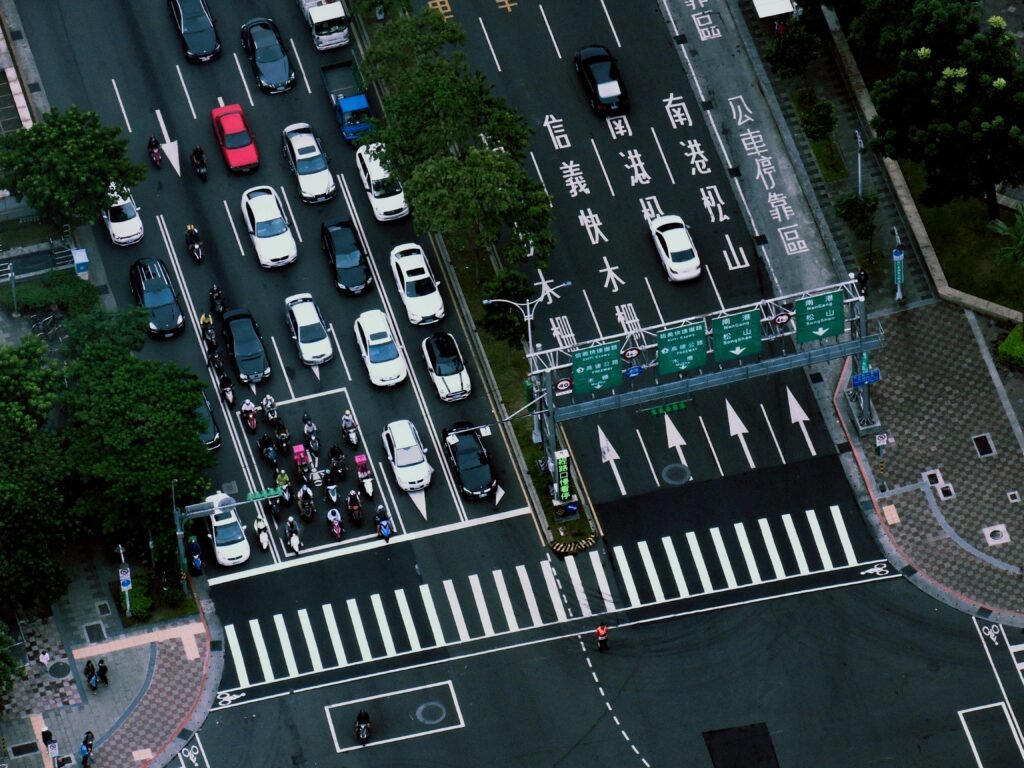 A bustling city intersection with vehicles and motorcycles captured from above.