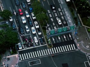 A bustling city intersection with vehicles and motorcycles captured from above.